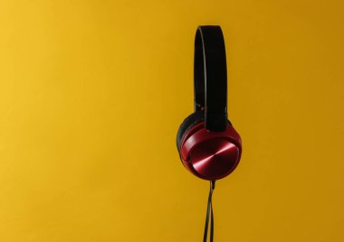 Kablolu yeni kulaklıklar. Sarı arka planda fotokopi çekilen kulaklıkların minimalist fotoğrafı. Siyah kırmızı DJ kulaklıklar.