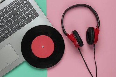 Kulaklığı ve pembe mavi pastel arka planda plağı olan bir Lptop. Retro dalga, popüler kültür, DJ ekipmanları. Üst görünüm