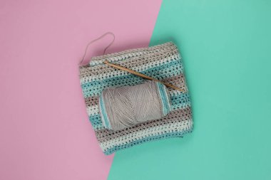 Yünlü iplikler ve mavi-pembe pastel arka planda örgü örmek için ahşap bir örgü. Üst görünüm