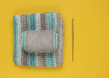 Sarı arka planda örgü örmek için yün iplikler ve ahşap örgü iplikleri olan iplik. Üst görünüm