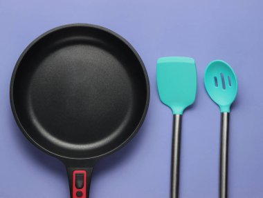 Mor arka planda spatula pişirilmiş yapışmaz tava. Minimalizm kavramı pişirmek. Stüdyo çekimi. Üst görünüm