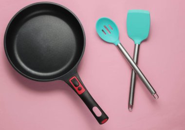Pembe pastel arka planda spatula pişirilmiş yapışmaz tava. Minimalizm kavramı pişirmek. Stüdyo çekimi. Üst görünüm