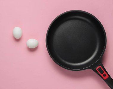 Pembe pastel arka planda yapışmaz tava ve yumurta. Minimalizm kavramı pişirmek. Üst görünüm