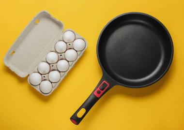 Yapışmayan tava ve sarı arka planda yumurta tepsisi. Minimalizm kavramı pişirmek. Üst görünüm