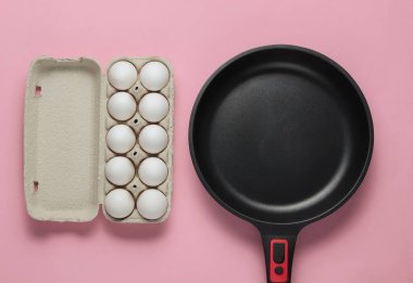 Yapışmayan tava ve pembe pastel arka planda yumurta tepsisi. Minimalizm kavramı pişirmek. Üst görünüm