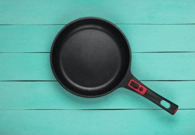 Mavi ahşap arka planda yapışmaz kaplamalı tava. Yemek ekipmanları. Üst görünüm