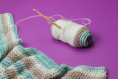 İplikli yün iplikler ve mor arka planda ahşap örgü kancası. Hobiler