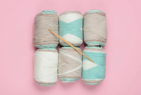 Pembe pastel arka planda yün iplik ve örgü kancası. Üst görünüm