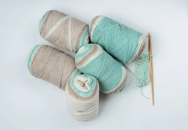 Beyaz arka planda bir sürü yün renkli iplikler, iplik, örgü kancaları var. Üst Manzara. Ev hobisi