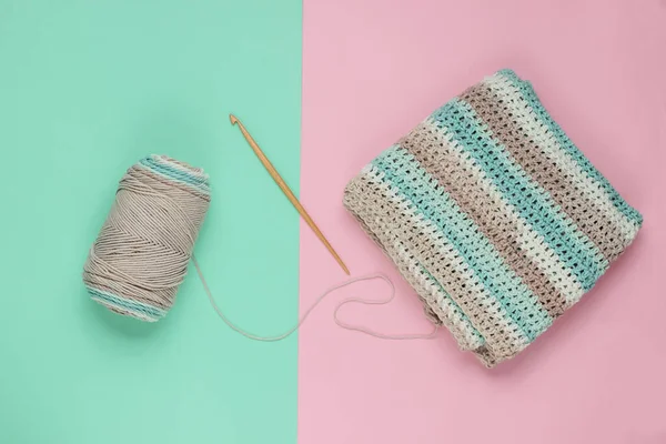 Yünlü iplikler ve mavi-pembe pastel arka planda örgü örmek için ahşap bir örgü. Üst görünüm