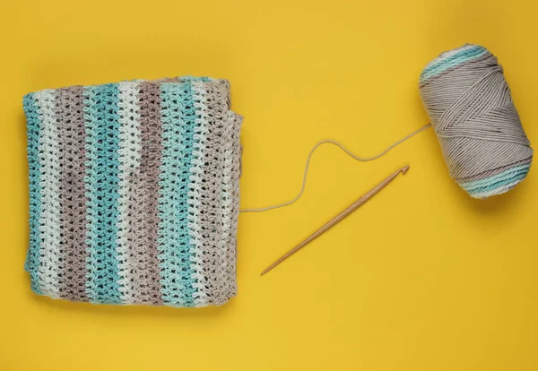 Sarı arka planda örgü örmek için yün iplikler ve ahşap örgü iplikleri olan iplik. Üst görünüm