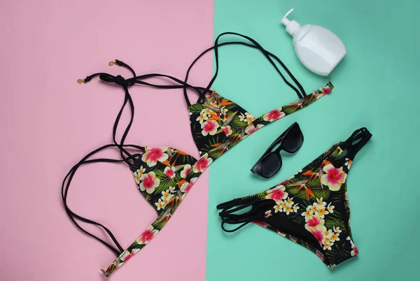 Pembe mavi pastel arka planda kadın mayosu ve plaj aksesuarları. Kadın mayosunun yukarıdan görünüşü. Yaz arkaplanı, sahilde tatil. Düz yatış, üst görünüm. 