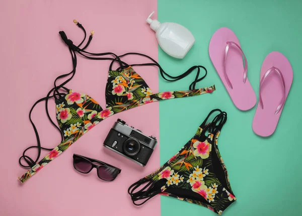 Yaz tatili kavramı. Pembe mavi pastel arka planda kadın mayosu ve plaj aksesuarları. Kadın mayosunun yukarıdan görünüşü. Düz yatış, üst görünüm. 