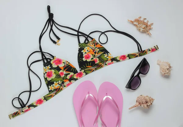 Beyaz arka planda kadın mayosu ve plaj aksesuarları. Kadın mayosunun yukarıdan görünüşü. Yaz arkaplanı, sahilde tatil. Düz yatış, üst görünüm. 