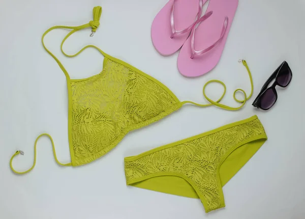 Beyaz arka planda kadın mayosu ve plaj aksesuarları. Kadın mayosunun yukarıdan görünüşü. Yaz arkaplanı, sahilde tatil. Düz yatış, üst görünüm. 