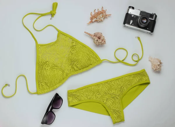 Beyaz arka planda kadın mayosu ve plaj aksesuarları. Kadın mayosunun yukarıdan görünüşü. Yaz arkaplanı, sahilde tatil. Düz yatış, üst görünüm. 