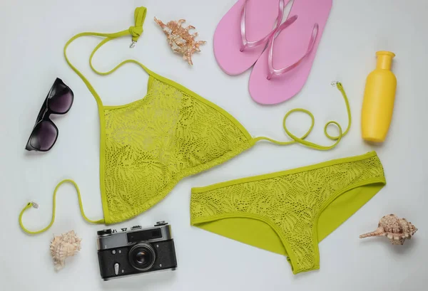 Beyaz arka planda kadın mayosu ve plaj aksesuarları. Kadın mayosunun yukarıdan görünüşü. Yaz arkaplanı, sahilde tatil. Düz yatış, üst görünüm. 