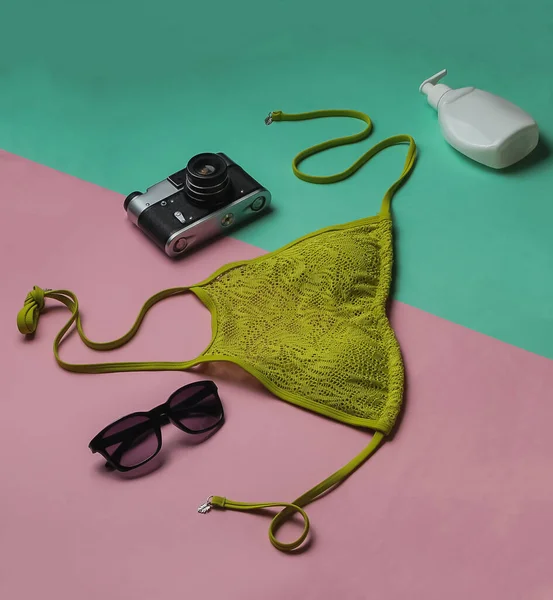 Yaz dönemi. Pembe mavi arka planda kadın mayosu ve plaj aksesuarları. Kadın mayosunun yukarıdan görünüşü. Plajda tatil. Düz yatış, üst görünüm. 