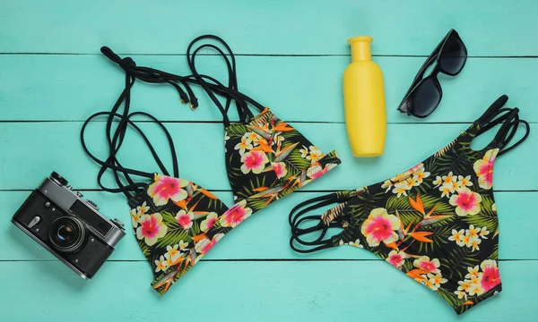 Yaz eğlencesi geçmişi. Mavi ahşap arka planda kadın mayosu ve plaj aksesuarları. Kadın mayosunun yukarıdan görünüşü. Plajda tatil. Düz yatış, üst görünüm. 