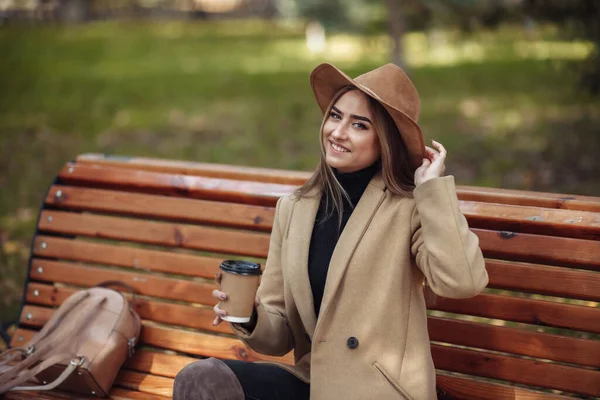 Mladá Atraktivní Žena Podzimním Oblečení Sedí Lavičce Pije Kávu Městském — Stock fotografie