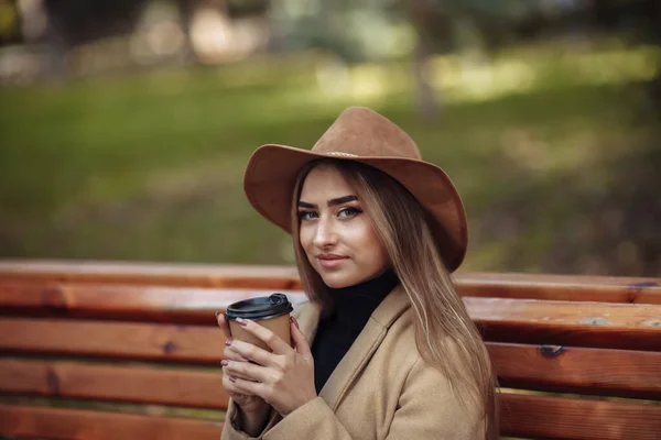 Mladá Atraktivní Žena Podzimním Oblečení Sedí Lavičce Pije Kávu Městském — Stock fotografie