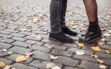 Romantik, aşk konsepti. Sonbahar şehrinde aşık genç bir çiftin ayakları. Genç çiftin nazik öpücüğü. Romantik bir randevuda aşıklar, kızlar parmak uçlarında durur erkeğini öpmek için