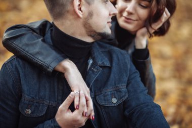 Genç aşıklar parkta düşen sonbahar yapraklarının bulanık arka planında birbirine sarılıyor. Romantik, aşk konsepti