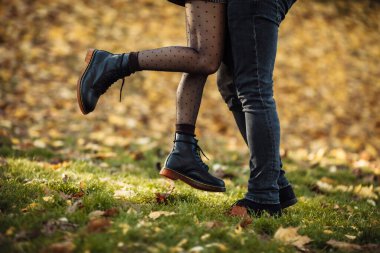 Romantik, aşk konsepti. Sonbahar parkında aşık genç bir çiftin ayakları. Genç çiftin nazik öpücüğü. Romantik bir randevuda aşıklar, kızlar erkeğini öper.