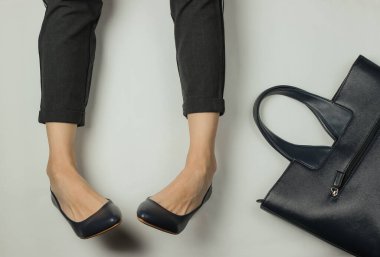 Pantolon giymiş kadın bacakları ve topuklu klasik ayakkabılar ve beyaz arka planda çanta. Üst Manzara. Güzellik ve moda stüdyosu