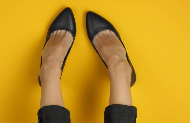 İş kadını düz konsept. Pantolon giymiş kadın bacakları ve sarı arka planda topuklu klasik ayakkabılar. Üst Manzara. Güzellik ve moda stüdyosu