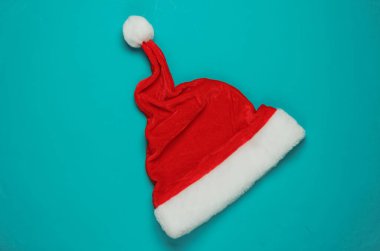 Mavi arka planda Noel Baba şapkası. Yeni yıl, Noel minimalist konsepti. Üst manzara, stüdyo çekimi..