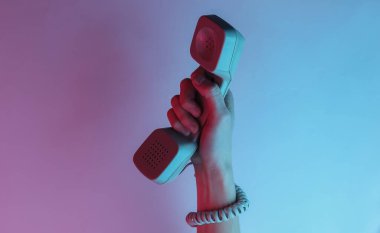 Kabloya sarılmış bir kadın el retro cep telefonunu tutuyor. Yaratıcı pop sanatının pembe neon rengi. Moda eğilimli aydınlatma. Gece lambası
