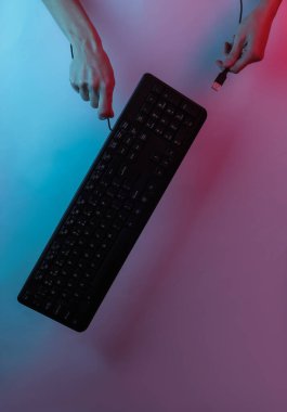 El bilgisayarın klavyesini tutuyor. Yaratıcı pop sanatının pembe neon rengi. Moda eğilimli aydınlatma. Gece lambası