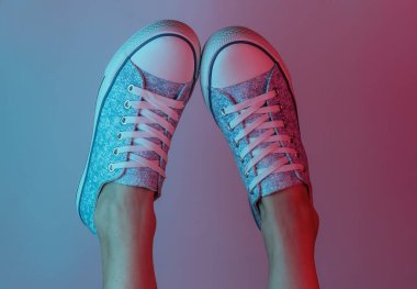 Spor ayakkabılı kadın ayakları. Yaratıcı pop sanatının pembe neon rengi. Moda eğilimli aydınlatma. Gece lambası