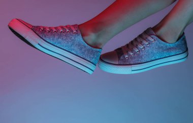 Spor ayakkabılı kadın ayakları. Yaratıcı pop sanatının pembe neon rengi. Moda eğilimli aydınlatma. Gece lambası