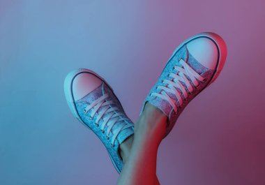 Spor ayakkabılı kadın ayakları. Yaratıcı pop sanatının pembe neon rengi. Moda eğilimli aydınlatma. Gece lambası