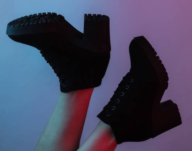 Siyah çizmeli kadın ayakları. Yaratıcı pop sanatının pembe neon rengi. Moda eğilimli aydınlatma. Gece lambası