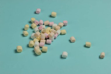 Mavi arka planda bir sürü mini marşmelov. Pastel renk eğilimi