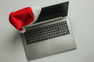 Beyaz arka planda Noel Baba şapkası olan dizüstü bilgisayar..