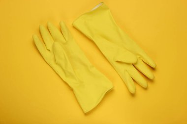 Sarı arka planı temizlemek için lateks eldivenler. Temizlik konsepti. Stüdyo çekimi. Üst görünüm