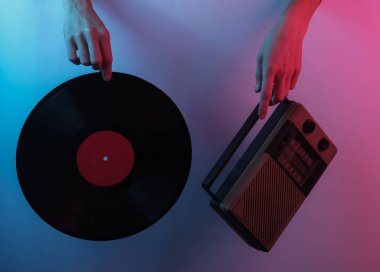 Retro dalga 80 'ler. Ellerinde radyo alıcısı ve plak plağı var. Yaratıcı pop sanatının pembe neon rengi. Moda eğilimli aydınlatma. Gece lambası