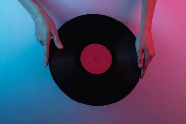 Retro dalga 80 'ler. Ellerinde plak plağı var. Yaratıcı pop sanatının pembe neon rengi. Moda eğilimli aydınlatma. Gece lambası