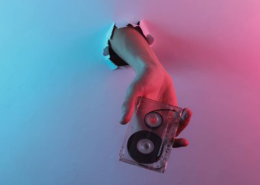 Yırtılan delikten ses kaseti geçiyor. Yaratıcı pop sanatının pembe neon rengi. Moda eğilimli aydınlatma. Gece lambası