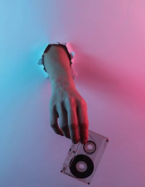 Yırtılan delikten ses kaseti geçiyor. Yaratıcı pop sanatının pembe neon rengi. Moda eğilimli aydınlatma. Gece lambası