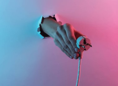 Yırtık delikten elinle elektrik fişini tut. Yaratıcı pop sanatının pembe neon rengi. Moda eğilimli aydınlatma. Gece lambası