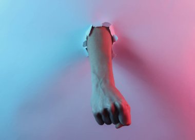 Mistik cadılar bayramı konsepti. Yırtık bir delikten geçen kadın yumruğu. Yaratıcı pop sanatının pembe neon rengi. Moda eğilimli aydınlatma. Gece lambası