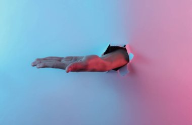 Mistik cadılar bayramı konsepti. Yırtık bir delikten geçen kadın avucu. Yaratıcı pop sanatının pembe neon rengi. Moda eğilimli aydınlatma. Gece lambası