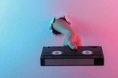 Yırtık delikten geçen bir video kaseti. Yaratıcı pop sanatının pembe neon rengi. Moda eğilimli aydınlatma. Gece lambası