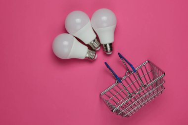 Pembe arka planda üç tane LED ampul ve alışveriş sepeti. Üst görünüm