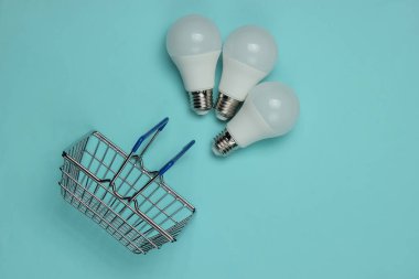 Mavi arka planda üç tane LED ampul ve alışveriş sepeti. Üst görünüm